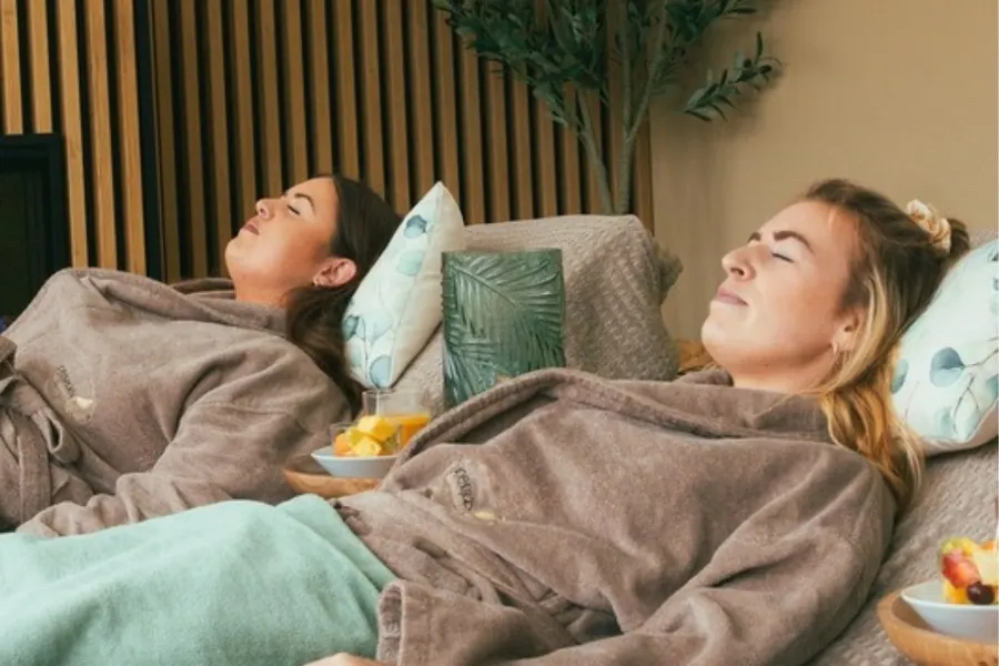 Two guests in robes relaxing on loungers at Revas Spa